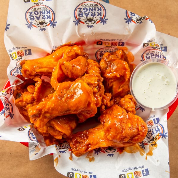 A red basket filled with Krab Kingz's buffalo wings and a side of ranch dressing.