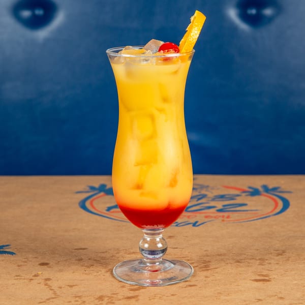 A vibrant Krab Kingz cocktail, yellow and red, garnished with an orange slice and cherry.